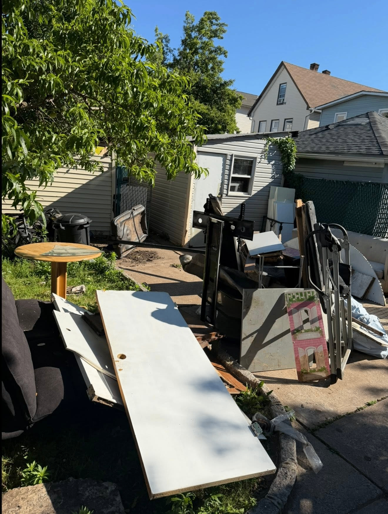 Before driveway junk removal in North Jersey — pile of household junk, boxes, and old furniture blocking the driveway